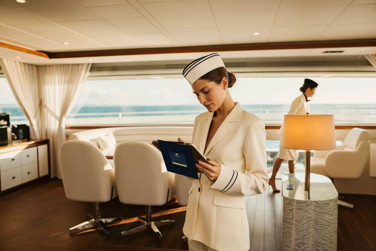 Una stewardess in divisa consulta il desk di Cortése-Crew su un tablet nel salone dello yacht